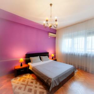 a bedroom with purple walls and a bed with two lamps at City Center Apartment in Bucharest