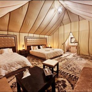 um quarto com 2 camas e uma mesa numa tenda em Desert Lover's Luxury Camp em Merzouga