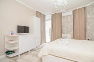 a white bedroom with a bed and a tv at Hotel Kalyan in Chişinău
