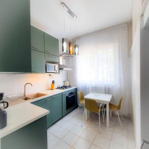 a kitchen with green cabinets and a table with chairs at City Center Apartment in Bucharest
