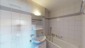un bagno piastrellato bianco con lavandino e vasca di Pracondu 1 001 - OUTDOOR & FUN apartment 8 pers a Nendaz