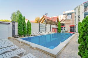 une piscine avec des chaises blanches et un bâtiment dans l'établissement Hotel Kalyan, à Chişinău