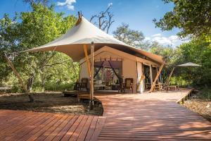 a tent with a table and chairs in it at Amber River Camp in Okavango Delta