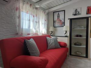 - un canapé rouge dans le salon doté d'une fenêtre dans l'établissement Mamà Apartment, à Augusta