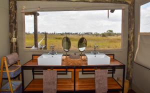 a bathroom with two sinks and a window at Amber River Camp in Okavango Delta