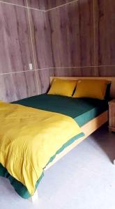 a bed with a yellow comforter in a room at Mr.Khanh Coffee in Xuân Trường