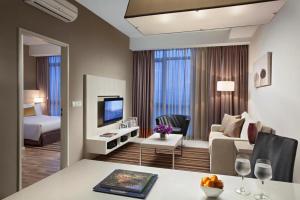 a hotel suite with a living room with a couch and a tv at Citadines Uplands Kuching in Kuching