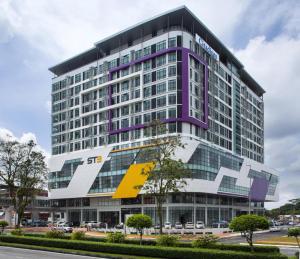 a tall building with a yellow and purple building at Citadines Uplands Kuching in Kuching