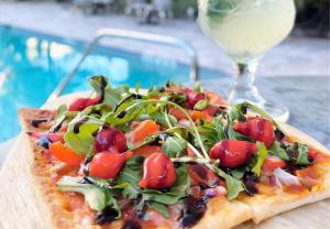 a pizza sitting on a table next to a glass of wine at Royal Palms Resort & Spa in Fort Lauderdale