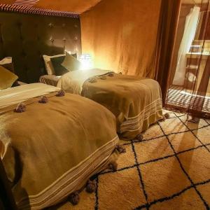 two beds sitting in a room with a window at Desert Lover's Luxury Camp in Merzouga