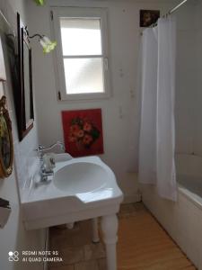 ein weißes Bad mit einem Waschbecken und einem Fenster in der Unterkunft Lulu in Castelmoron-sur-Lot