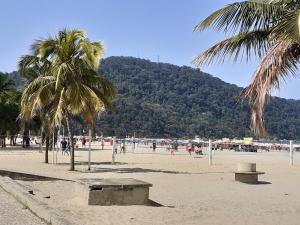 people on a beach with palm trees and a mountain at Good Vibes in Praia Grande