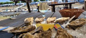 un tavolo in legno con ostriche e un bicchiere di vino di Superbe appartement Arcachon a La Teste-de-Buch
