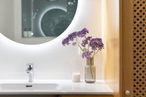 a vase of purple flowers sitting on a bathroom sink at Home2Book Stylish Apartment Alcalá Beach in Alcalá +25 photos