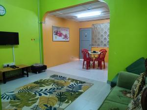 a living room with a table and chairs and a green wall at KLUANG BARAT HOMESTAY in Kluang