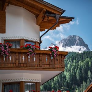 uma varanda com flores e uma montanha ao fundo em Garni Hotel Franca b&b em Selva di Val Gardena