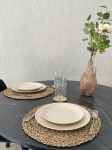 a table with two plates and a vase with flowers at Superbe logement près de Bruxelles avec spa privé in Brussels