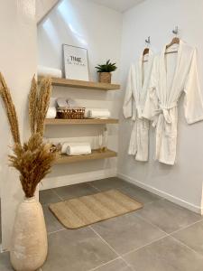 a bathroom with white coats and towels on shelves at Superbe logement près de Bruxelles avec spa privé in Brussels