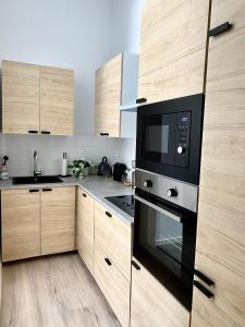 a kitchen with wooden cabinets and a black microwave at Superbe logement près de Bruxelles avec spa privé in Brussels
