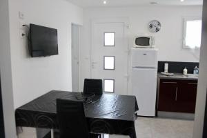 Il comprend une cuisine équipée d'une table et d'un réfrigérateur blanc. dans l'établissement La petite maison by PÓM, à Lorient
