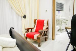 ein Krankenhauszimmer mit einem roten Stuhl und einem Bett in der Unterkunft Pitikwe Hill Guesthouse in Lobatse