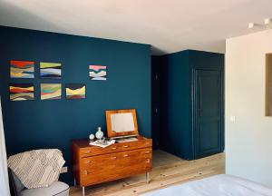 a bedroom with a blue wall with a dresser and a mirror at Maison Henri Namur in Namur