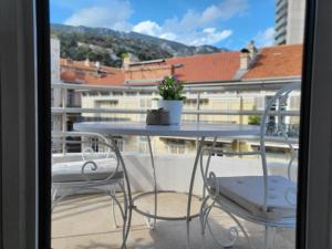una mesa con 2 sillas y una maceta en el balcón en Appartement Centre ville carré d'Or, en Montecarlo
