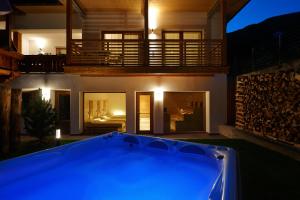 a blue pool in front of a house at night at Alpin Stile Hotel in Laion