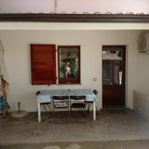 einen Tisch mit zwei Stühlen und eine Person in einem Fenster in der Unterkunft Margherita Holiday House in Porto Pino