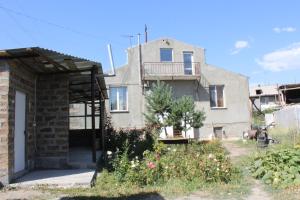 una casa antigua con un balcón en el lateral. en Runada B&B en Sisian