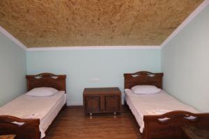 Habitación con 2 camas y mesa de madera. en Runada B&B en Sisian