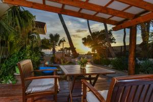 a wooden table and chairs on a deck with the sunset at Aruba Sunset Beach Studios in Palm-Eagle Beach