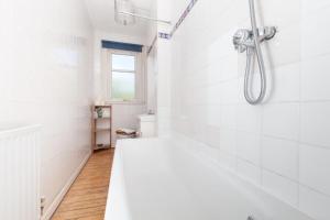エディンバラにあるSpacious 2-Bed Homely Base by Water of Leithの白いバスルーム(バスタブ、シャワー付)