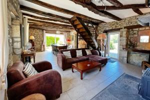 sala de estar con muebles de cuero y pared de piedra. en Presbytère de Chauffour-sur-Vell, en Chauffour-sur-Vell