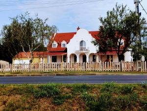 una casa blanca con un techo rojo detrás de una valla en ReGoRi Ház en Balatongyörök