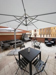 eine Terrasse mit einem Tisch und Stühlen unter einem Sonnenschirm in der Unterkunft Domus Flavia B&B in Rom