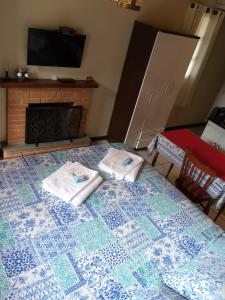 ein Wohnzimmer mit einem Kamin und Handtüchern auf dem Bett in der Unterkunft Chalé MJF in Monte Verde