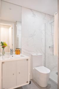 La salle de bains blanche est pourvue d'une douche et de toilettes. dans l'établissement Wanderlust, by Bolhão Residences, à Porto
