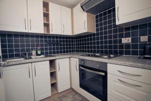 a kitchen with white cabinets and blue tiles at Flat 1 Bellevue in Bristol