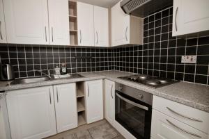 a kitchen with white cabinets and a sink and a stove at Flat 1 Bellevue in Bristol