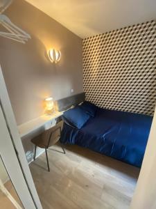 niewielka sypialnia z niebieskim łóżkiem i biurkiem w obiekcie Cosy courcelles w Paryżu
