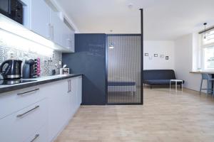 a kitchen with white cabinets and a blue wall at City Hall view Apartment Liberec in Liberec
