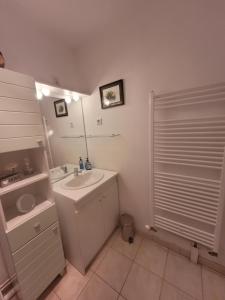 ein weißes Badezimmer mit einem Waschbecken und einem Spiegel in der Unterkunft Le Papé logement meublé tourisme 3 étoiles in Villers-sur-Mer