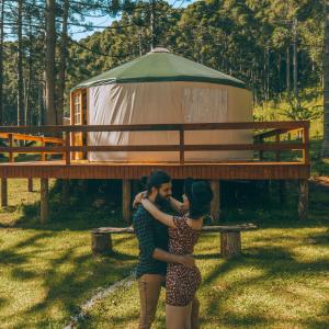 um homem e uma mulher abraçados em frente a uma tenda em Estancia Las Araucarias em Canela