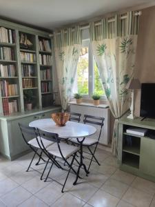 ein Esszimmer mit einem Tisch, Stühlen und einem Fenster in der Unterkunft Le Papé logement meublé tourisme 3 étoiles in Villers-sur-Mer