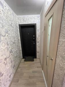 een hal met een zwarte deur en een trap bij 2-х комнатная Казахстан 97 in Öskemen