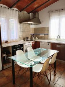 uma cozinha com uma mesa de vidro e cadeiras brancas em Casa de Campo Los Manueles Ideal Perros Pet Friendly em Gójar