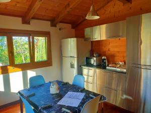 una cucina con tavolo con sedie e frigorifero di Chalet Collalto con Piscina a Cerratina