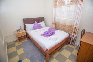 Dormitorio pequeño con cama con almohadas moradas en Heritage Villa Hotel & Accomodation, en Kericho