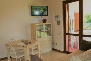 a living room with a table and a tv on the wall at Verdemare Sardegna Due Villette in Villasimius